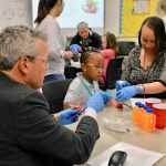 AstraZeneca’s Ruud Dobber (left) extracts DNA from strawberries with a family at the Delaware Biotechnology Institute’s Family STEAM Night.