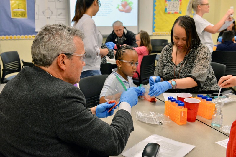 AstraZeneca’s Ruud Dobber (left) extracts DNA from strawberries with a family at the Delaware Biotechnology Institute’s Family STEAM Night.