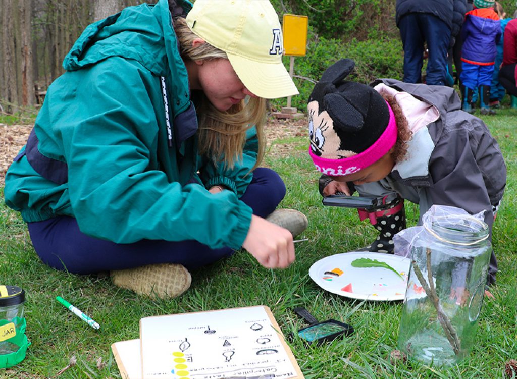 Teacher and student examine caterpillars outside at the UD Lab School