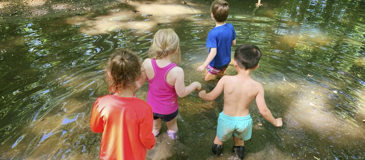 Four children walking in creek at UD Lab School