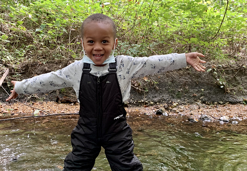 Child exploring a stream outside at the UD Lab School